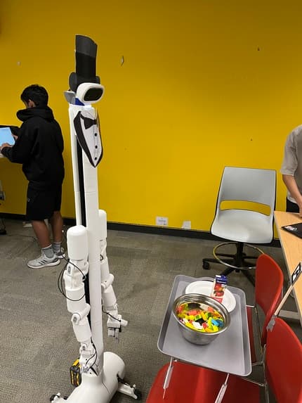 The BracketBot fitted with a custom tray and dressed as a butler with a top hat and bow tie